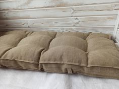 a brown pillow sitting on top of a white bed