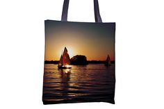 two sailboats in the water at sunset on a tote bag that is hanging from a hook