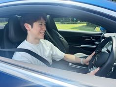 a man sitting in the driver's seat of a blue car