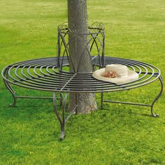 a hat is sitting on top of a metal rack near a tree in the grass