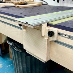 a workbench with some tools on top of it and two black trash cans