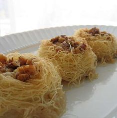 three pieces of food on a plate with noodles and meats in the middle, ready to be eaten