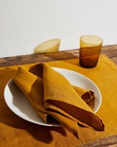 a napkin is folded on a plate with a glass and banana in the back ground