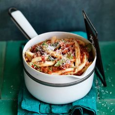 a white bowl filled with pasta on top of a blue napkin and black spoons