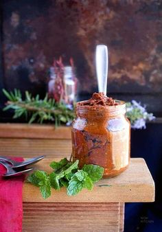 a jar filled with food sitting on top of a table next to utensils