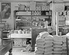 an old black and white photo of a store with lots of bags on the counter