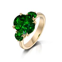 three stone ring in yellow gold with green stones on the sides and an oval shape