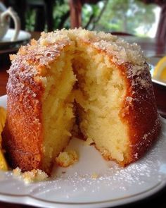 a white plate topped with a cake covered in powdered sugar next to lemon wedges