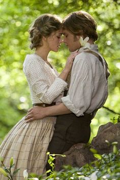 a man and woman standing next to each other in the woods