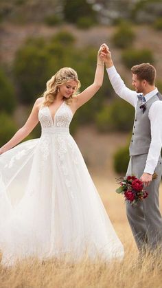 a bride and groom are holding hands in the middle of a field with tall grass