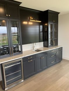 a kitchen with gray cabinets and stainless steel appliances in the center, along with wood flooring