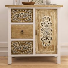 an ornate wooden cabinet with three drawers and two vases on top of the drawer