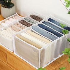 an open drawer with several pairs of folded clothes in it on top of a wooden table