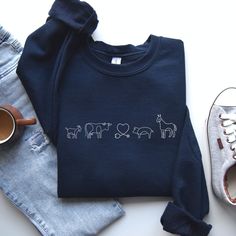 a pair of shoes and a sweatshirt with animals on it, next to some jeans