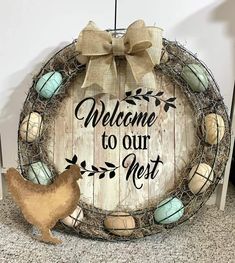 a welcome to our nest sign hanging on a wall with a chicken figurine next to it