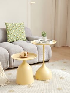 two tables sitting on top of each other in front of a gray couch and white rug