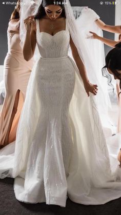 a woman in a wedding dress standing next to two other women wearing dresses and veils