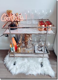 a bar cart filled with drinks and glasses on top of a white fur covered floor