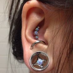 a person with some piercings on their ear and one is wearing a star shaped ring