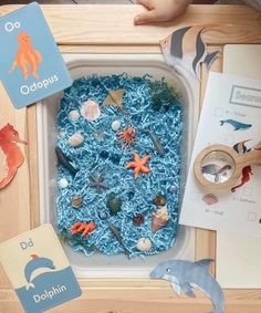 a child's play tray filled with blue sand and sea animals