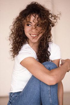 a woman with curly hair sitting on the floor