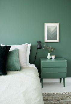 a bedroom with green walls and white bedding, two nightstands and a poster on the wall