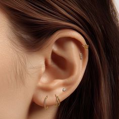 a woman's ear with three piercings on top of her head and one behind the ear