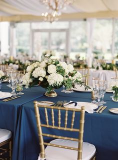 the table is set with blue linens and white flowers