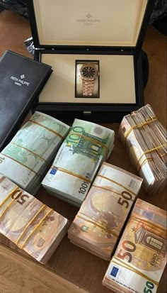 several stacks of money sitting on top of a table next to a watch and wallet