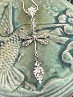 a close up of a dragonfly pendant on a plate with a bird in the background