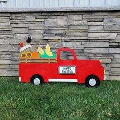 a red truck is parked in front of a stone wall with a sign that says happy fall's day