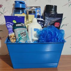 a blue tub filled with lots of different types of hygiene products on top of a wooden table