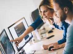 two people looking at a computer screen with their hands on the monitor and pointing to it