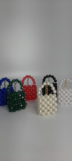 four beaded purses in different colors and sizes on a white surface with pearls