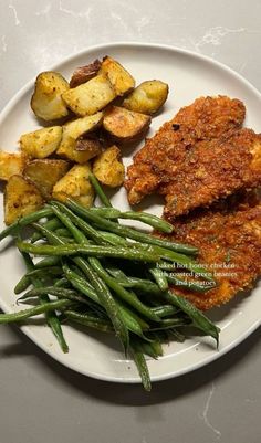 a white plate topped with meat, potatoes and green beans on top of a table