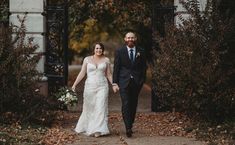 a bride and groom walking through an archway