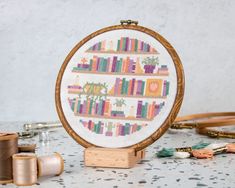 there is a cross stitch pattern on the table with thread spools and sewing needles