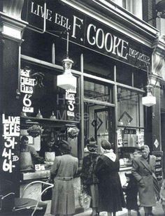 an old black and white photo of people standing in front of a store