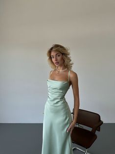 a woman in a green dress standing next to a chair