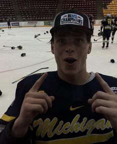 a young man standing in front of an ice rink holding his finger up to the camera