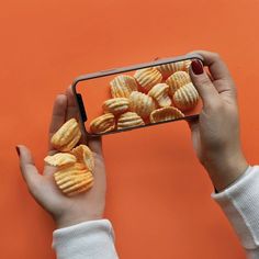 a person holding up a cell phone with some food on the screen and chips in front of them