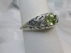 Natural Peridot Ring Etched Wedding Design#160 Made To Order Here we have a Victorian/Edwardian reproduction ring in sterling silver with a stunning natural peridot gemstone. This full cut round peridot gem is 6mm in diameter. The inside of the band is marked 925 for sterling. Notice the beautiful floral design of the silver filigree setting and band. This is a lovely rendition of an Antique filigree ring; and it is ready to wear. A gift ring box is included and all rings are shipped in the box Antique May Birthstone Wedding Rings, Antique May Birthstone Rings For Wedding, Heirloom Peridot Wedding Jewelry, Lime Green Gemstone Wedding Jewelry, Green Solitaire Ring For Wedding, Lime Green Gemstone Jewelry For Wedding, Wedding Ring With Hallmarked Peridot, Wedding Filigree Ring With May Birthstone, Lime Green Peridot Jewelry For Wedding