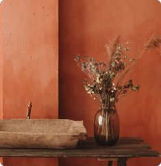 a vase filled with flowers sitting on top of a table next to a wooden bowl