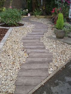 a wooden walkway surrounded by gravel and flowers