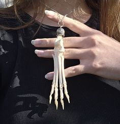 a woman wearing a skeleton necklace and holding onto her hand with long bones attached to it