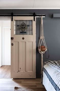 a bedroom with a bed and a hanging chair in it's corner, next to an open door