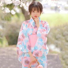 a woman in a kimono holding a basket and looking at the camera with her hand under her chin