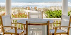 a table and chairs on a porch with the ocean in the background