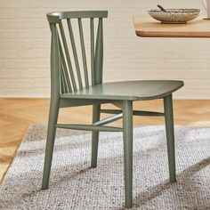 a green chair sitting on top of a rug next to a wooden table and bowl