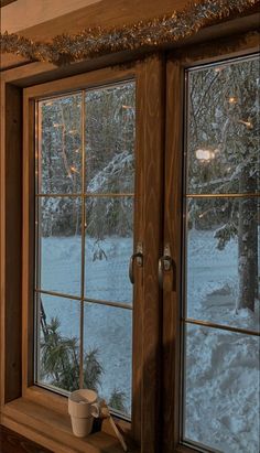 there is a cup sitting on the window sill in front of the snow covered yard